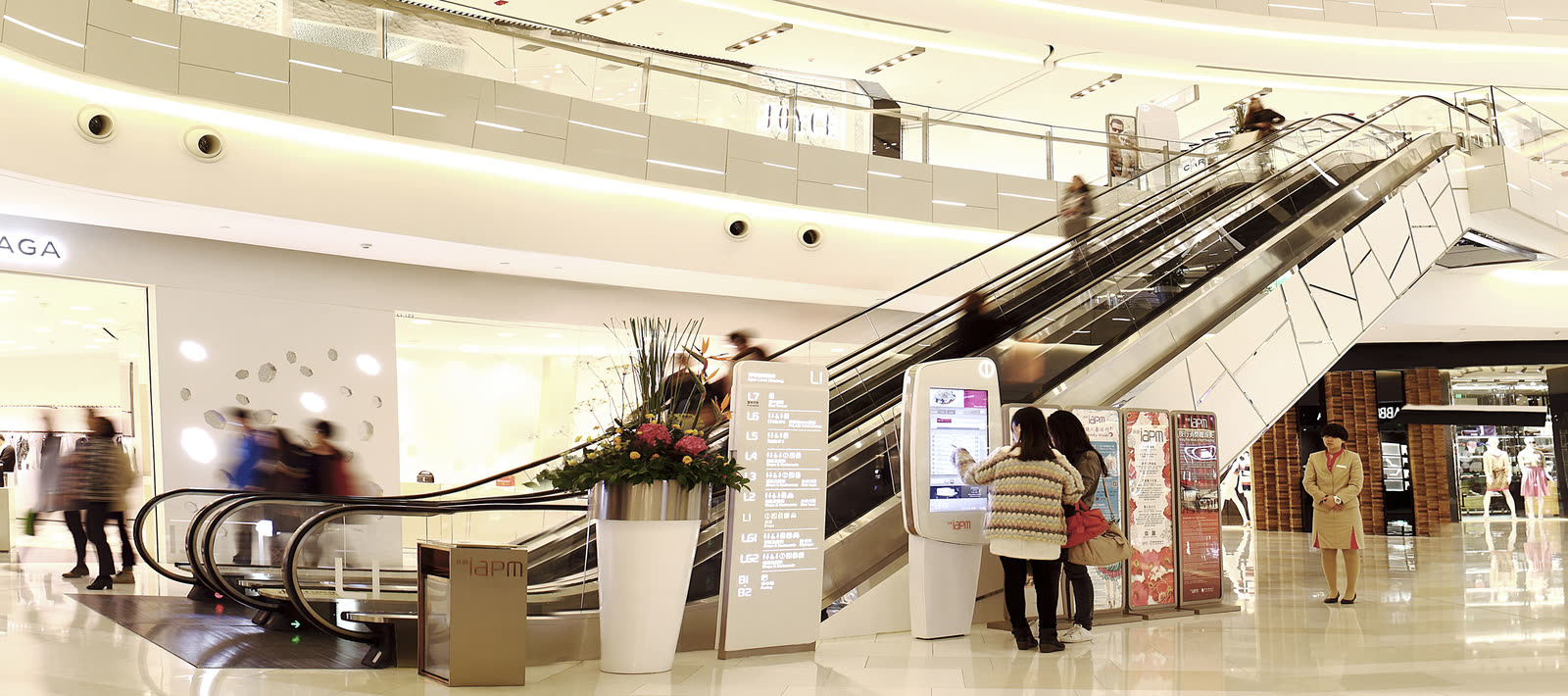 Shoppers using Abuzz wayfinding directories beside the escalators of a shopping mall
