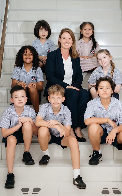 AISB head of school seated on steps with a group of students in uniform