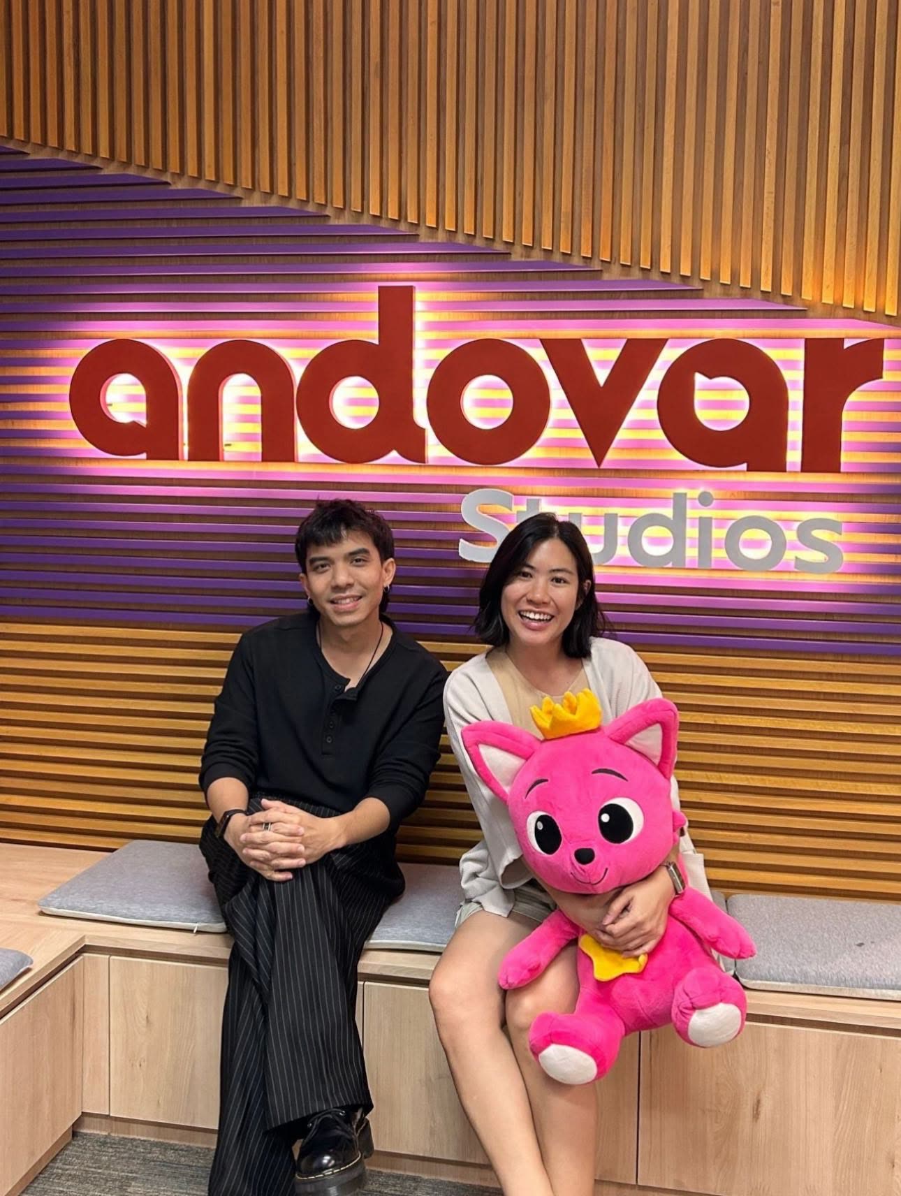 Andovar Studios team members with the Pinkfong mascot beneath the studio sign