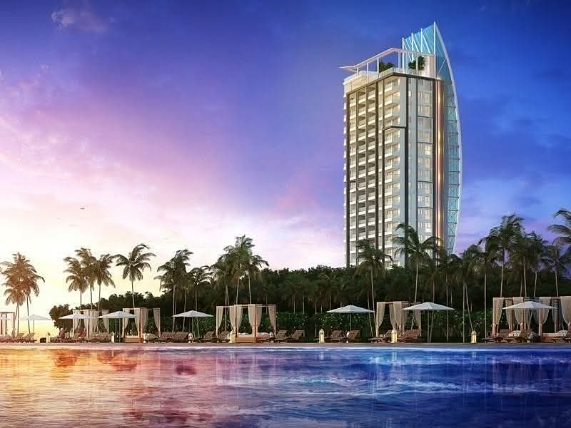 Elysium Residences tower rising above the beachfront at sunset