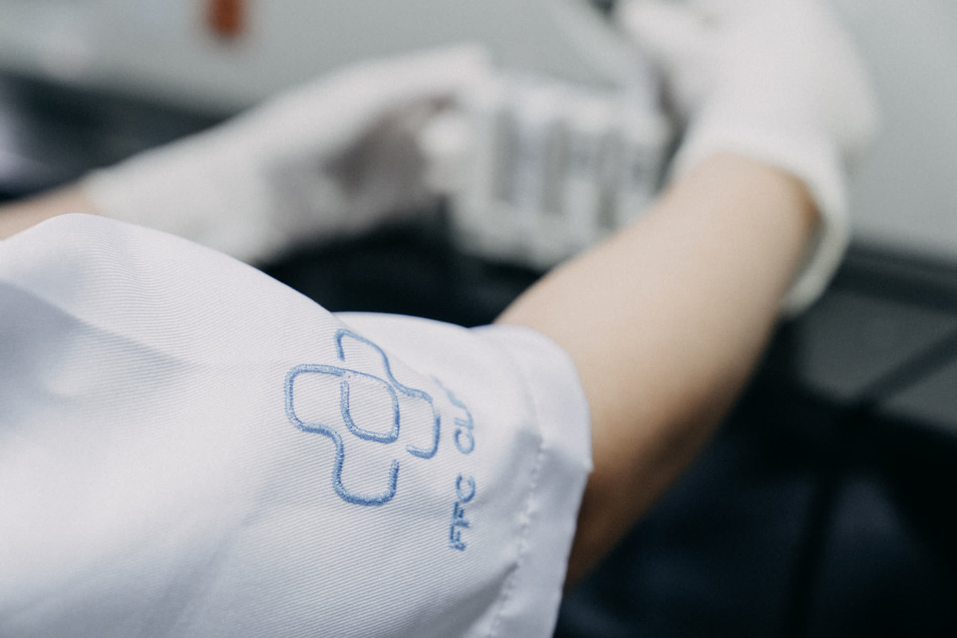 Laboratory technician handling samples in a branded First Fertility lab coat