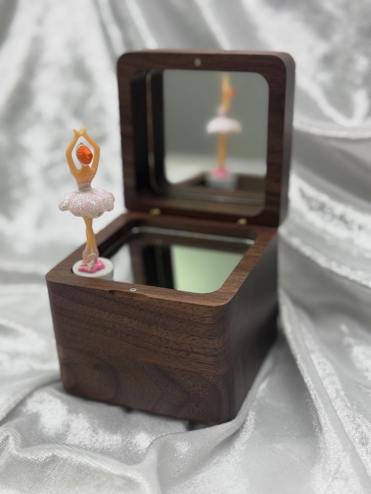 A wooden music box with a spinning ballerina figurine