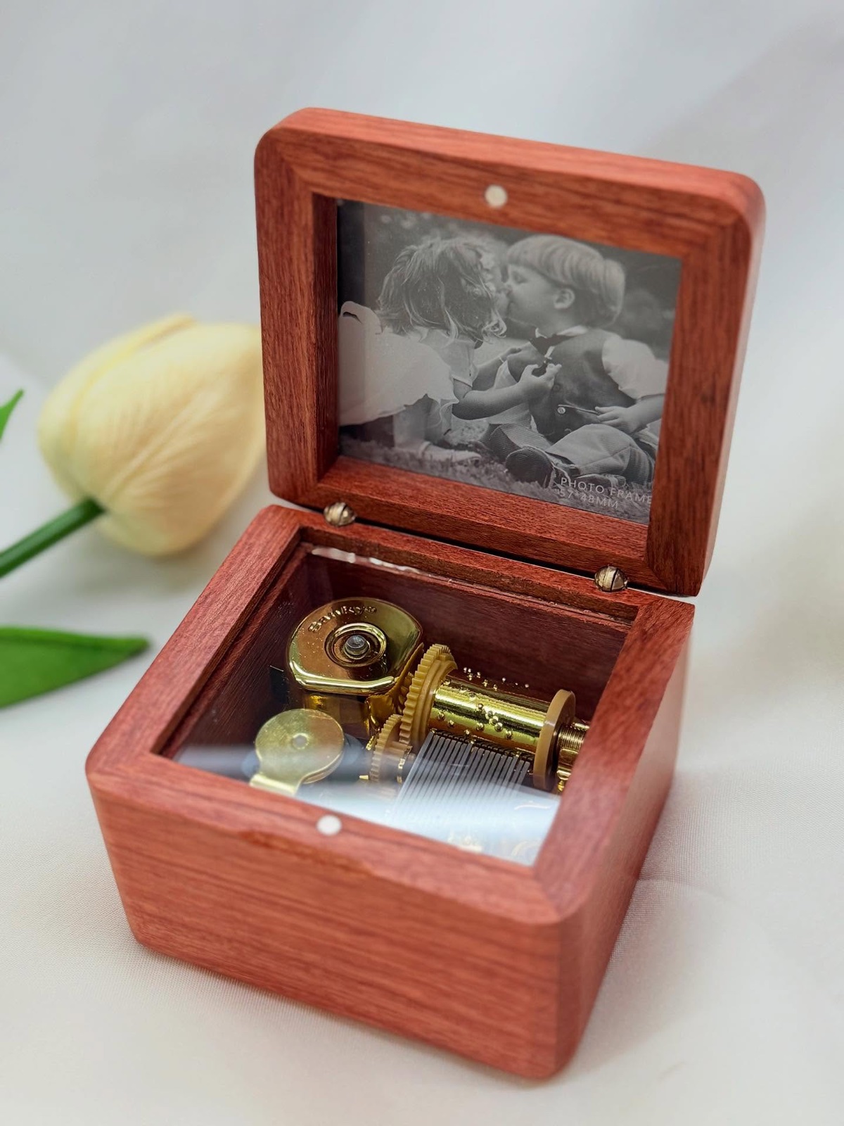An open music box with a photo engraved inside the lid