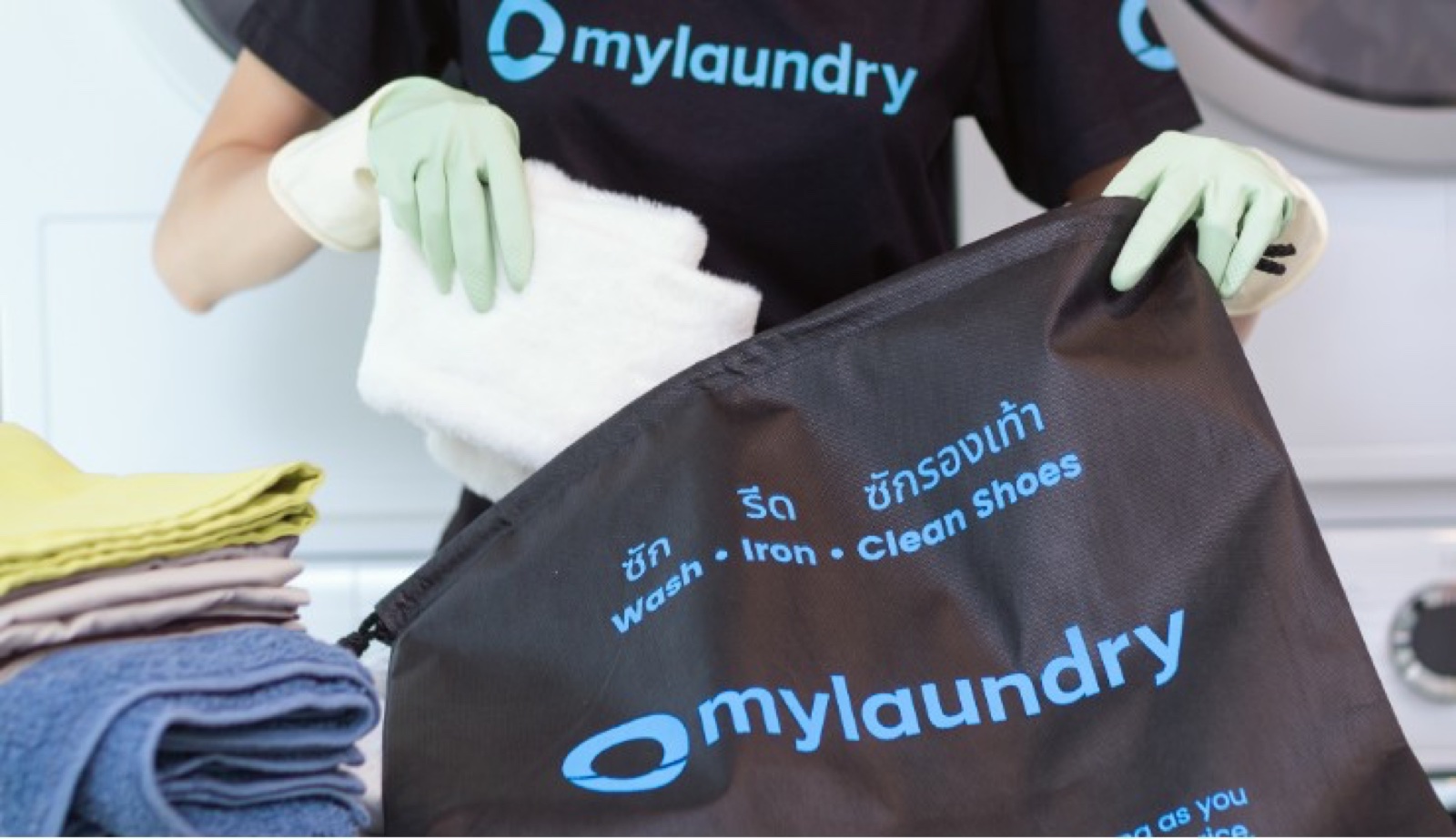 A mylaundry staff member packing folded laundry into a branded bag