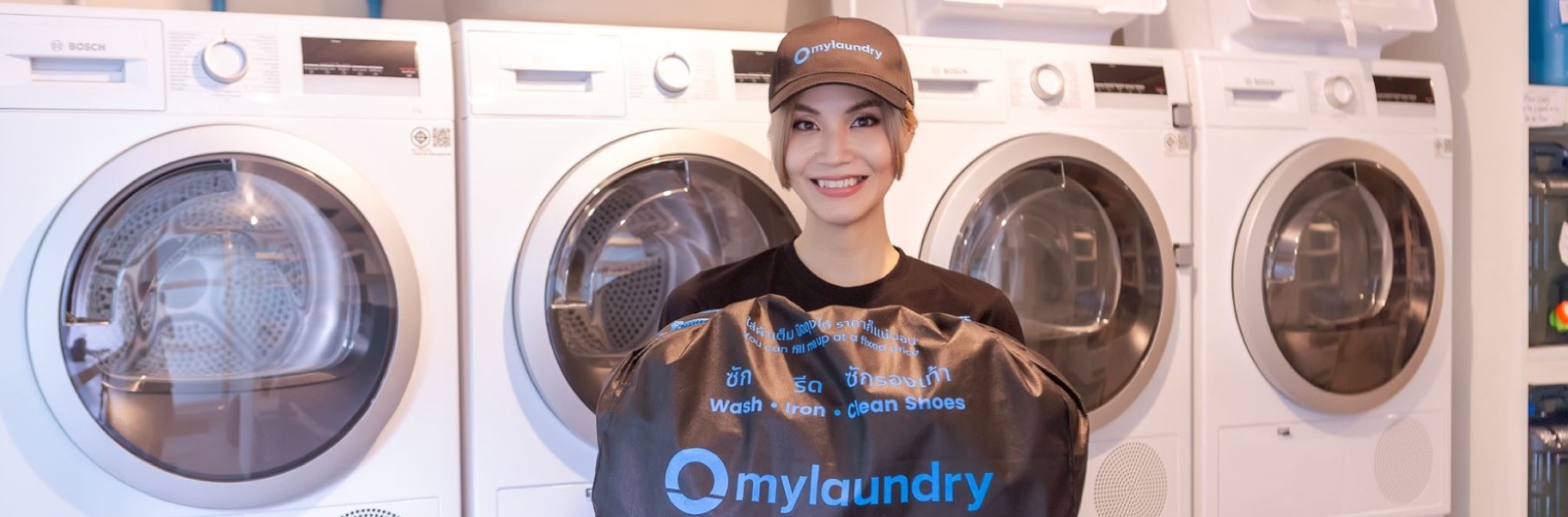 A mylaundry staff member in front of a row of washing machines