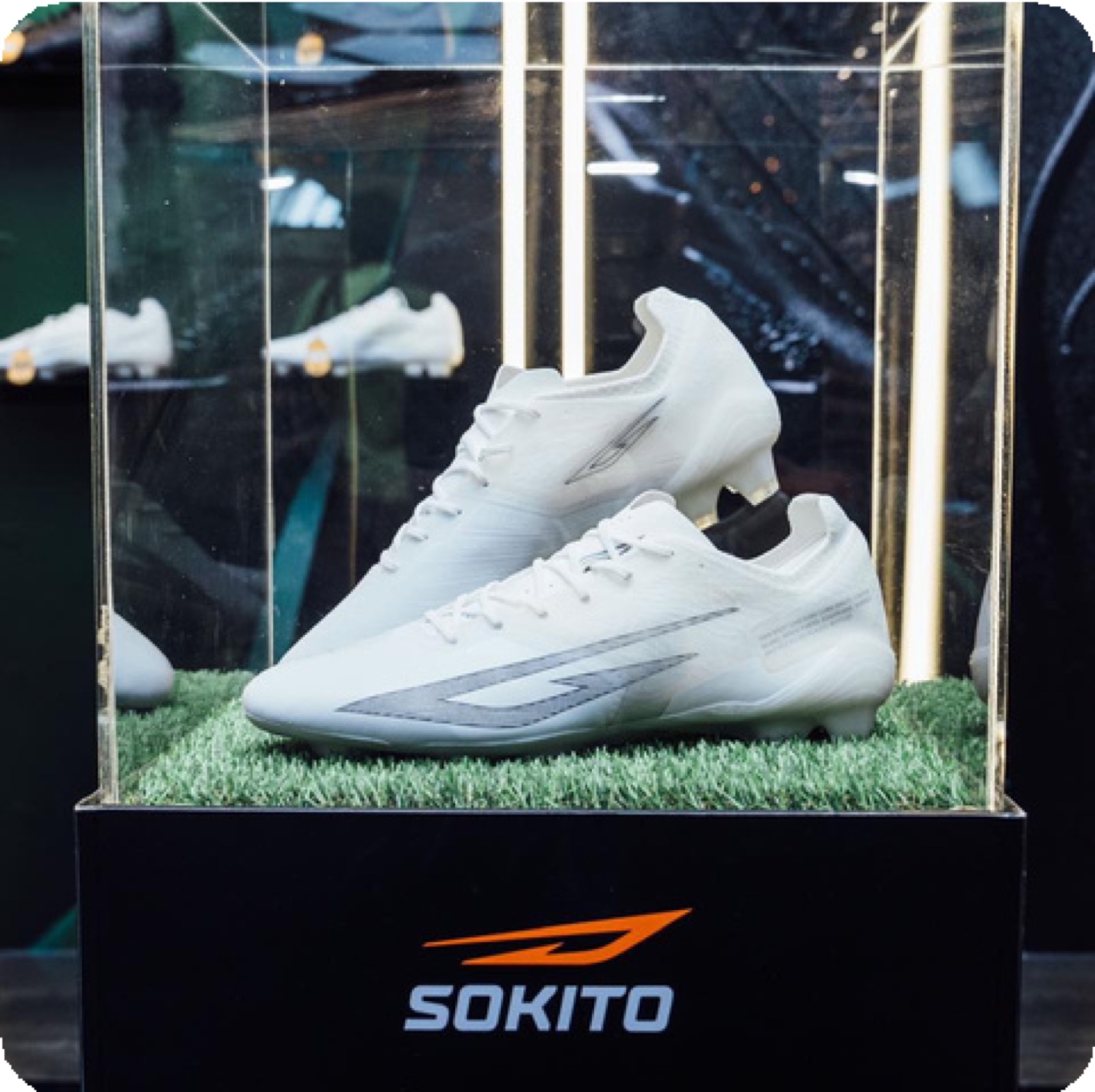A white Sokito football boot displayed in a case