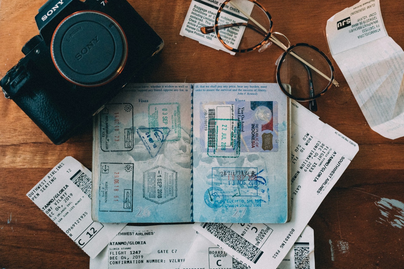 A passport filled with visa stamps beside a camera and glasses
