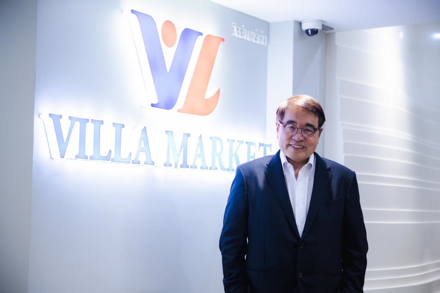 Villa Market executive beside the company logo at the head office
